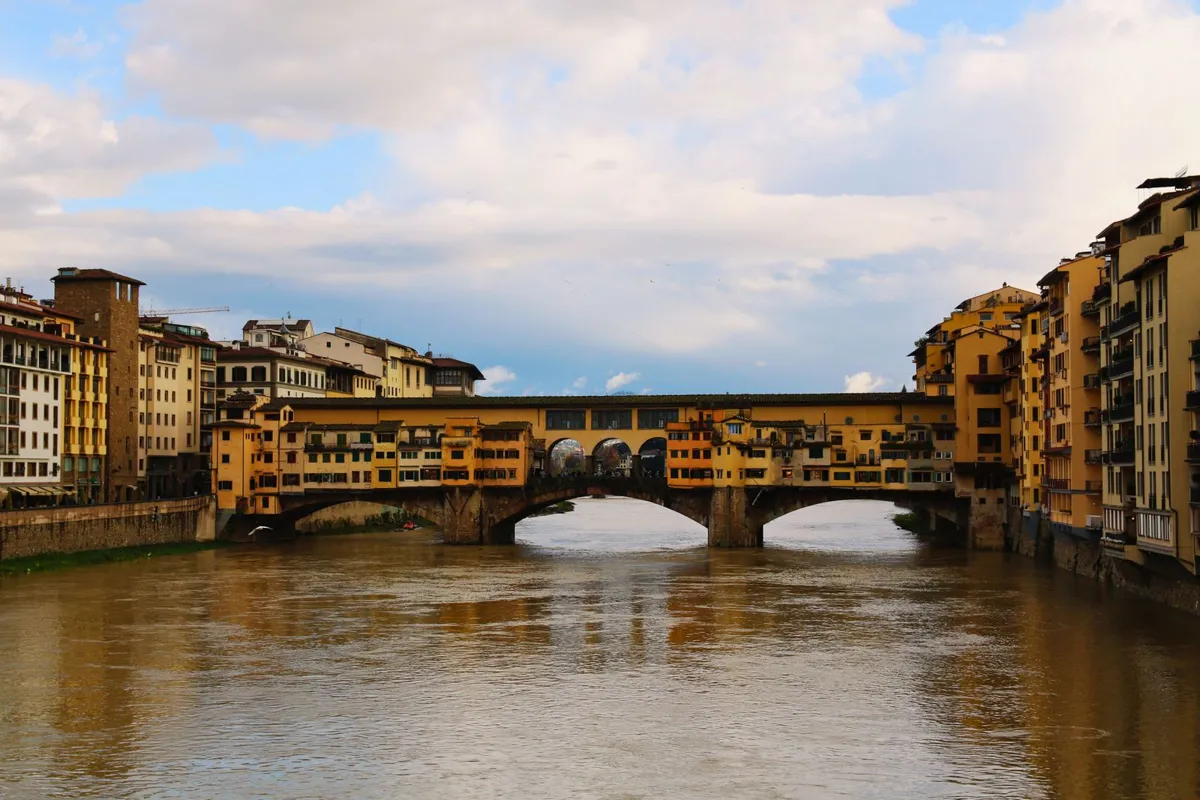 Ponte Vecchio spanning the Arno beneath cloudy skies