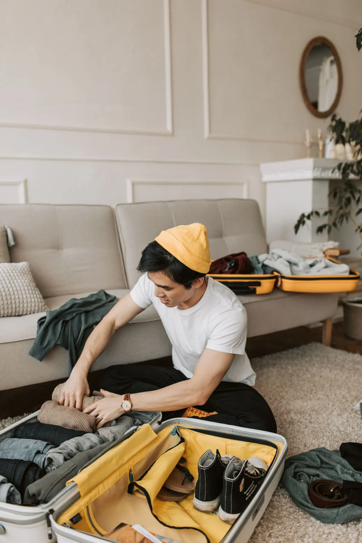 A traveler arranging clothes inside a yellow suitcase