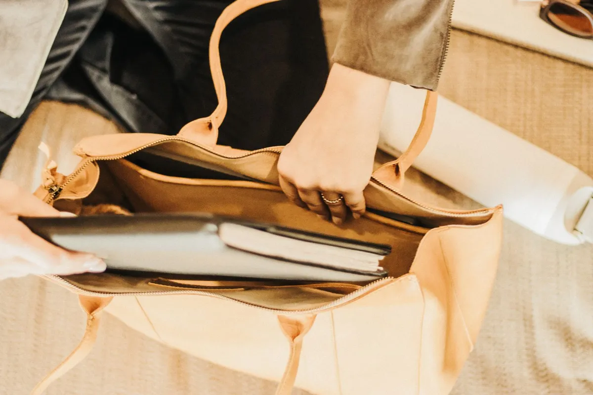 A leather tote containing a laptop and notebook