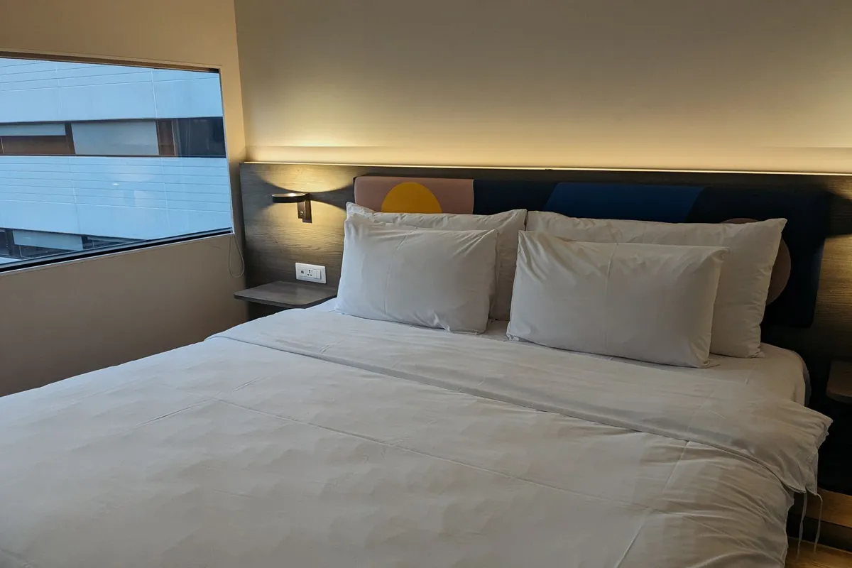 Hotel bed beside a large window