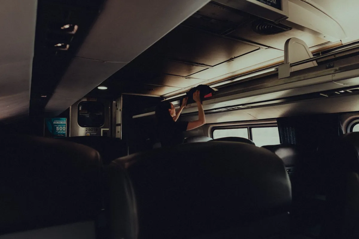 Traveler putting luggage on a train storage rack