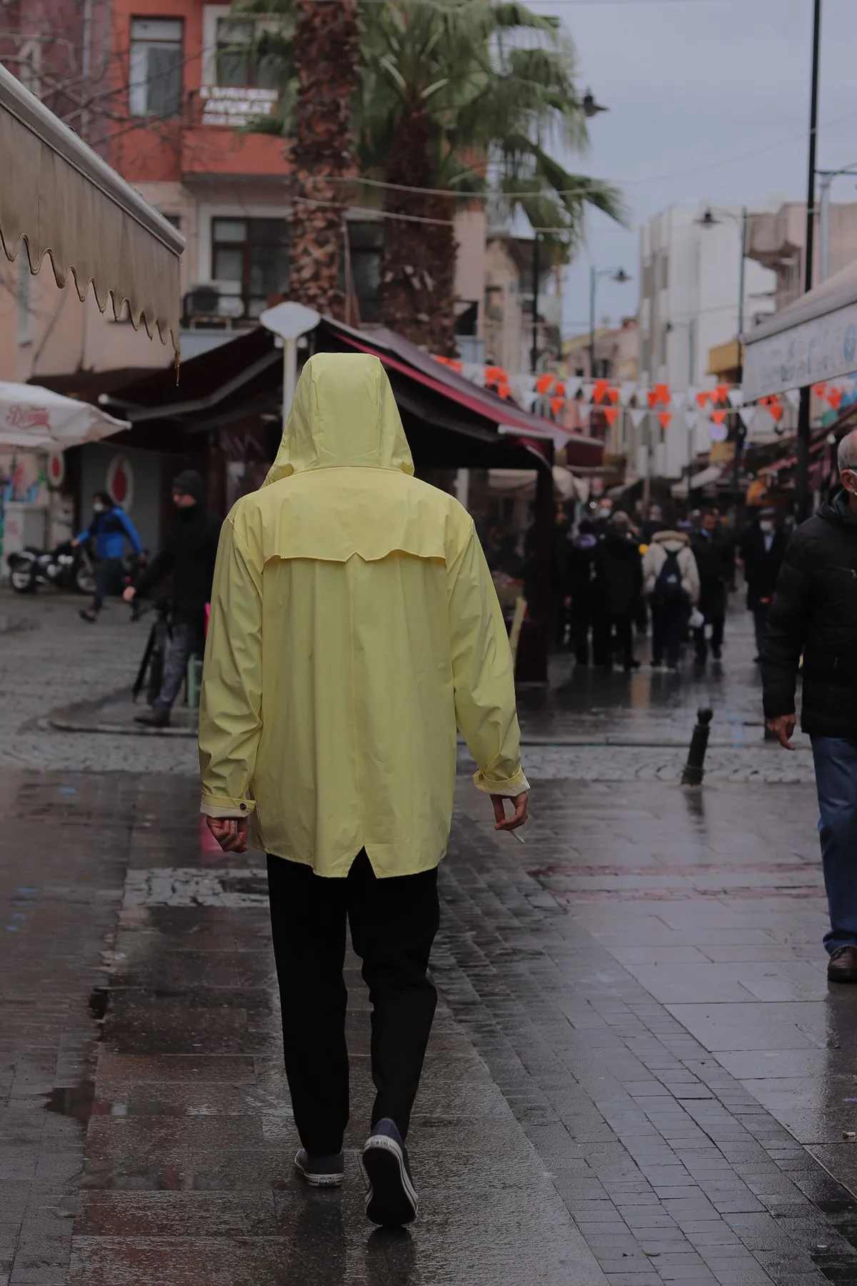 A hooded yellow rain layer on a wet city sidewalk